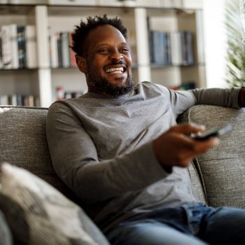 man watching tv in living room and laughing