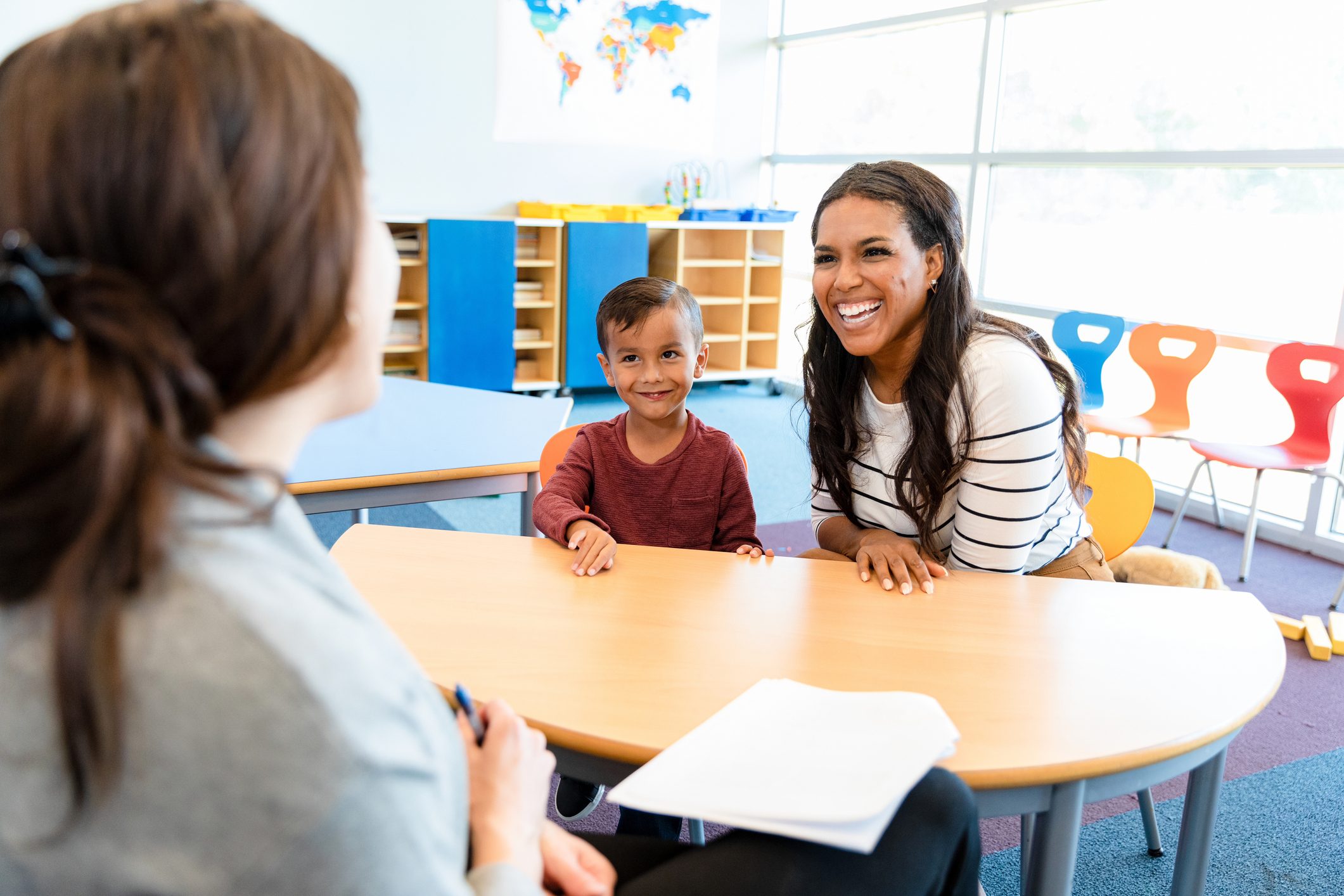 Cute boy watches mom and teacher in meeting