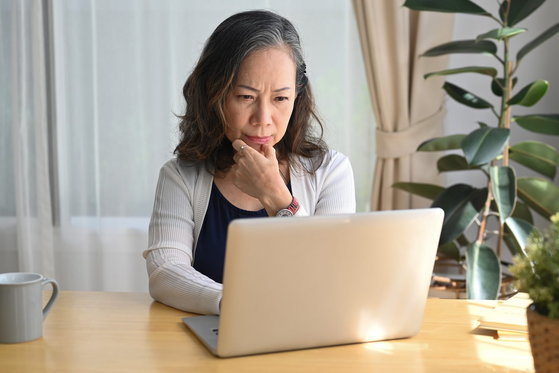 Serious mature woman checking business email during remote working from home.