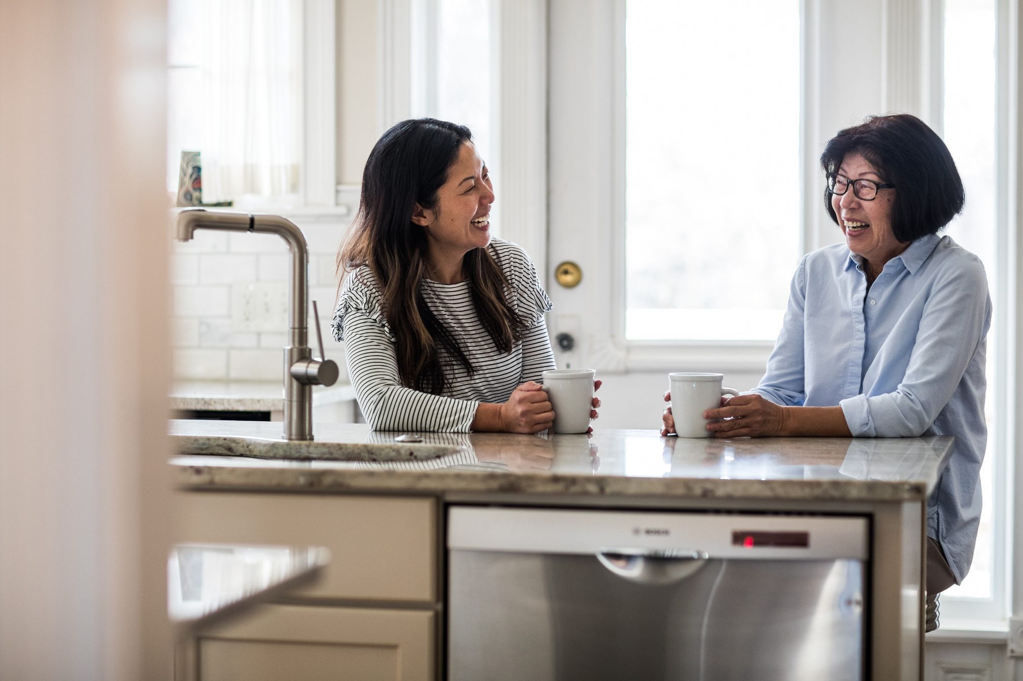 mother and adult daughter having coffee in kitchen