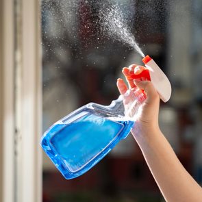 hand spraying a bottle of windex on a window