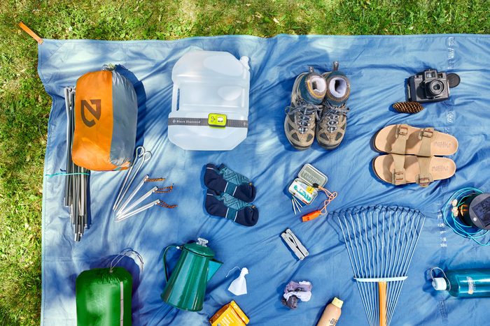 Camping supplies spread out on a tarp in the grass