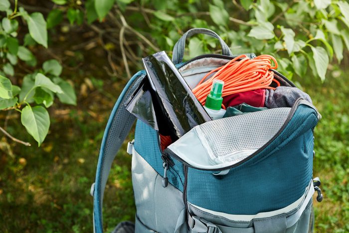 a contractors trash bag sticking out of an open backpack full of camping supplies