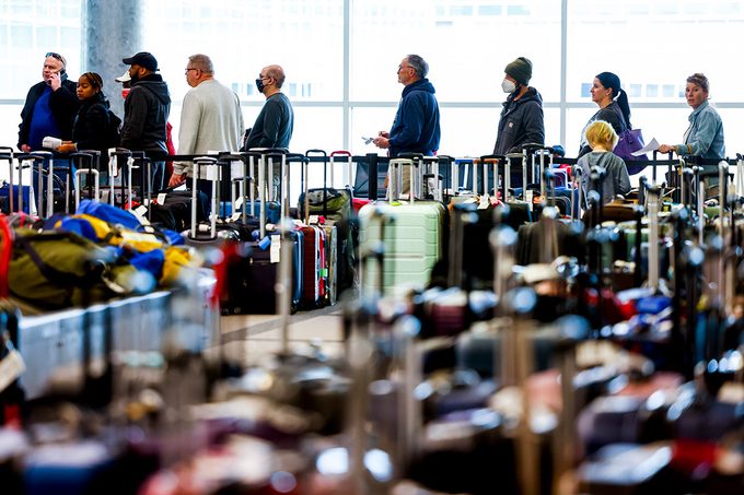 Travelers wait in line before they are allowed to search for their luggage in a baggage holding area for Southwest Airlines at Denver International Airport