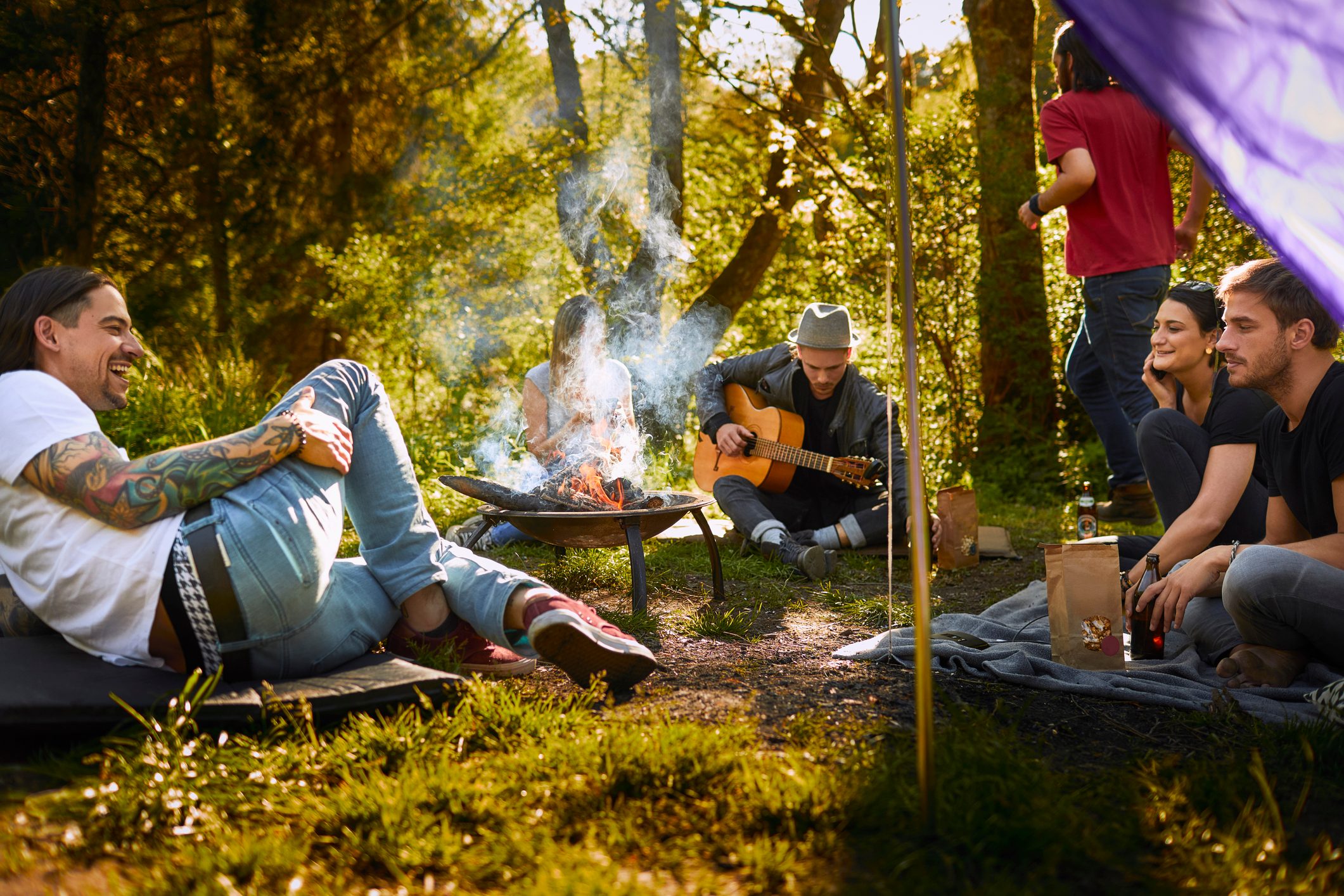 Friends sitting together in nature around campfire