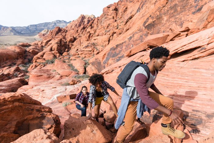 Friends hiking on rock formations during sunny day