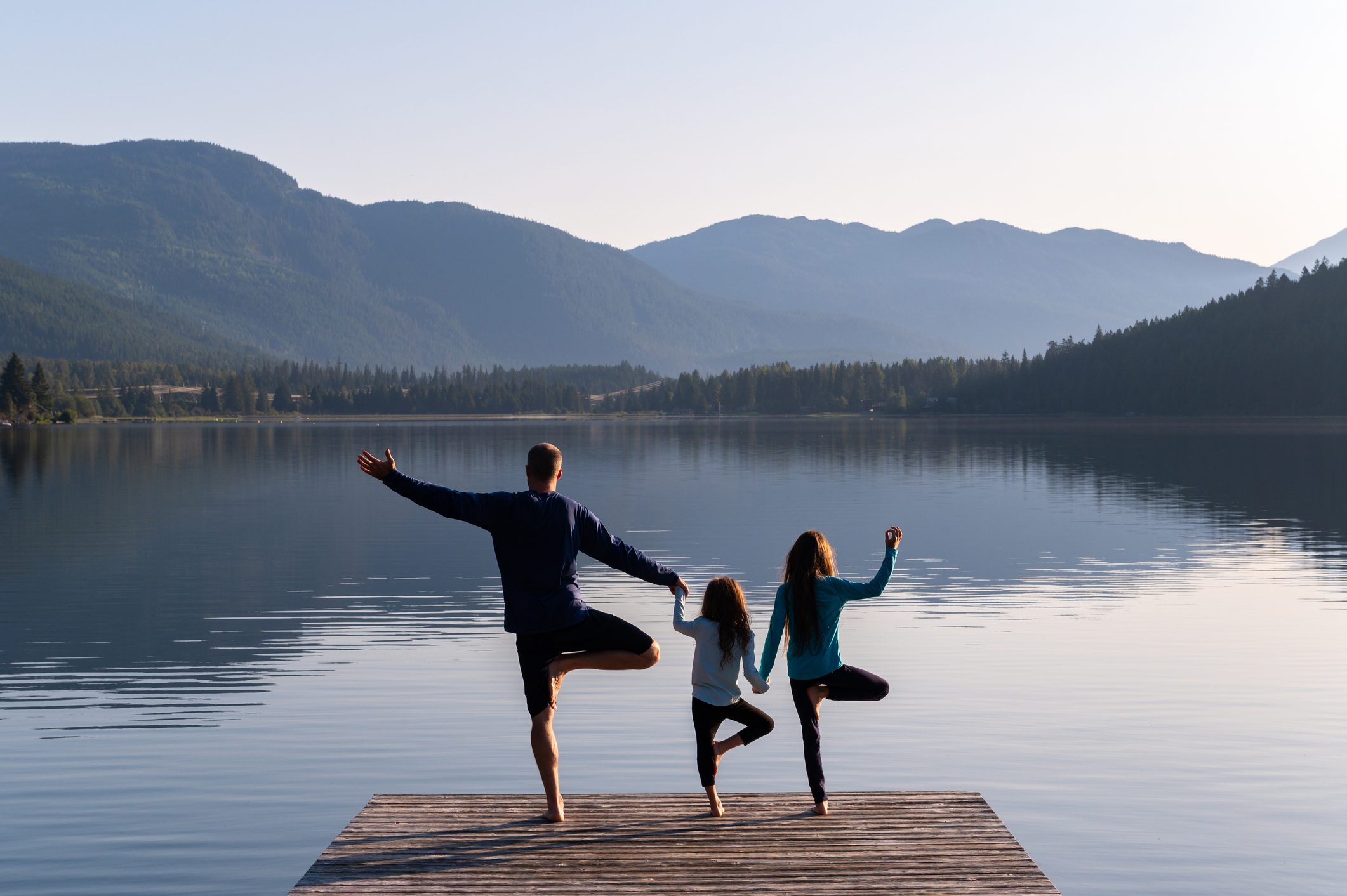 Family practising yoga outdoors