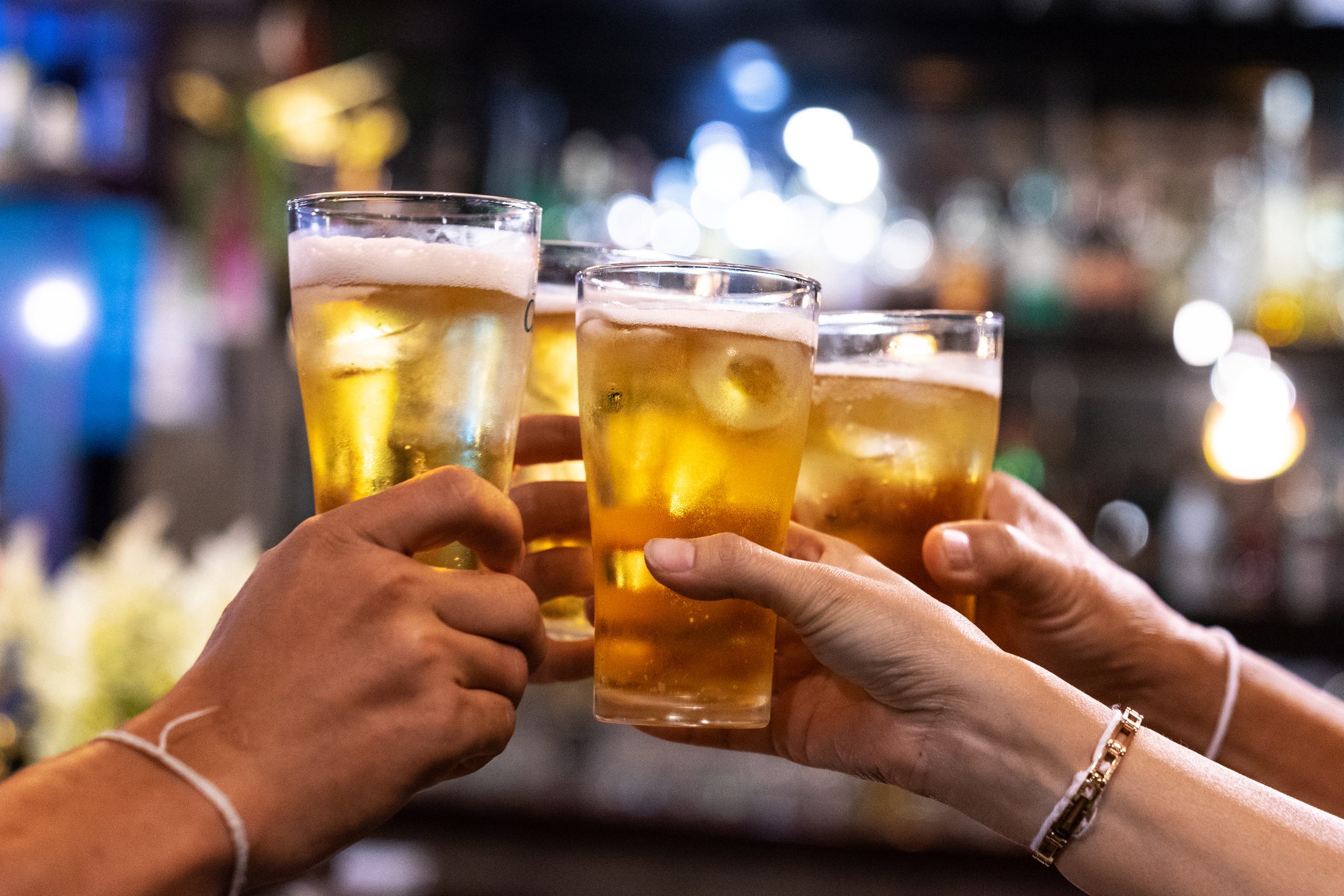 Group of happy friends drinking and toasting beer at brewery bar restaurant - Friendship concept with young people having fun together at cool vintage pub - Focus on middle pint glass - High iso image