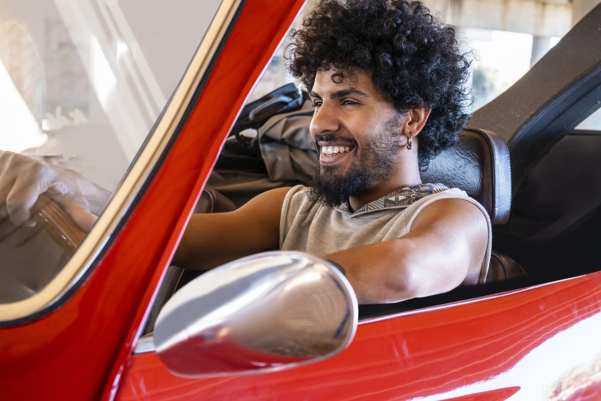 Ethnic young guide man driving a red generic car convertible