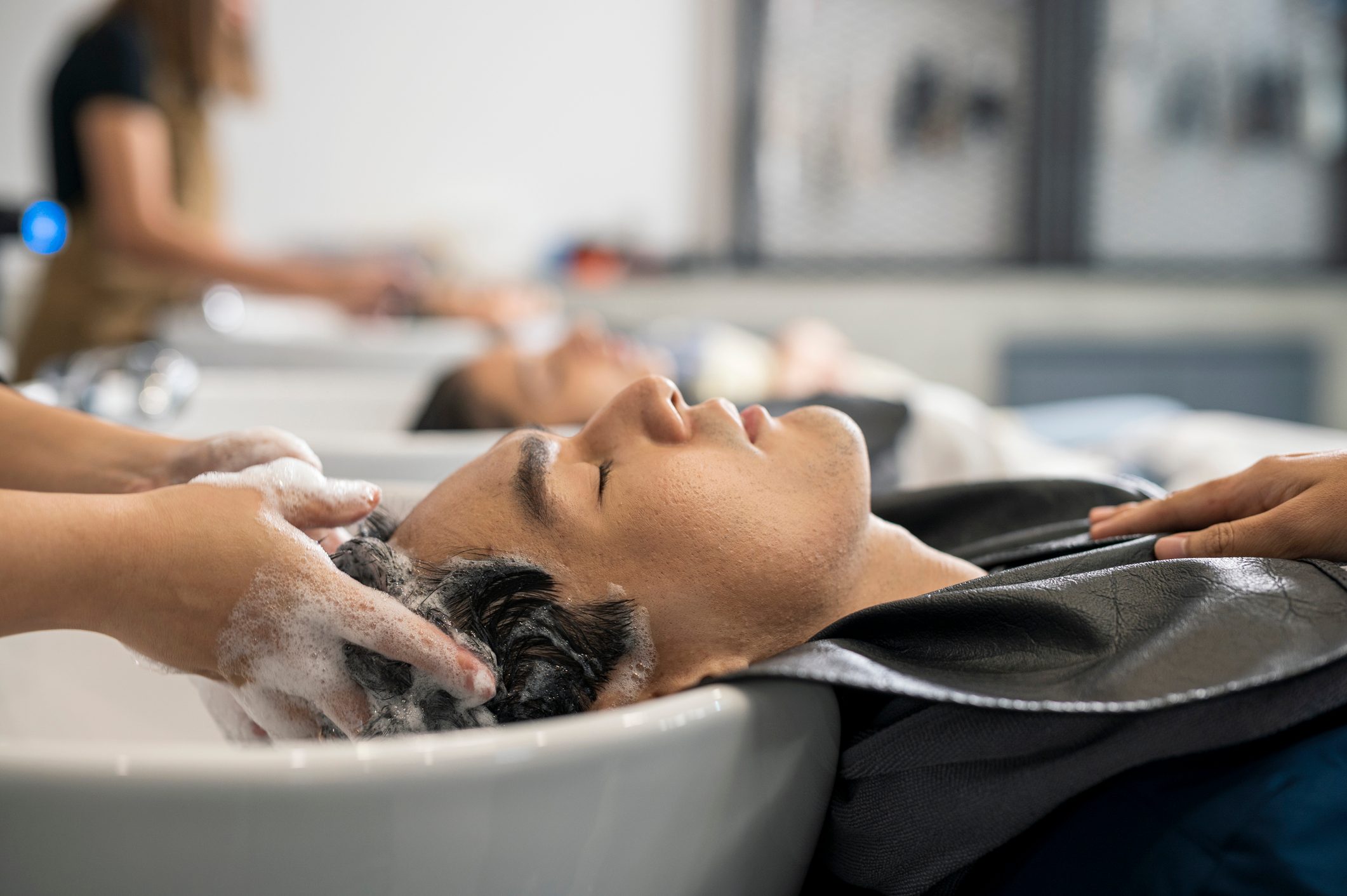 Man getting hair washed by hairdresser at hair salon. Hair salon beauty treatment for everyone.