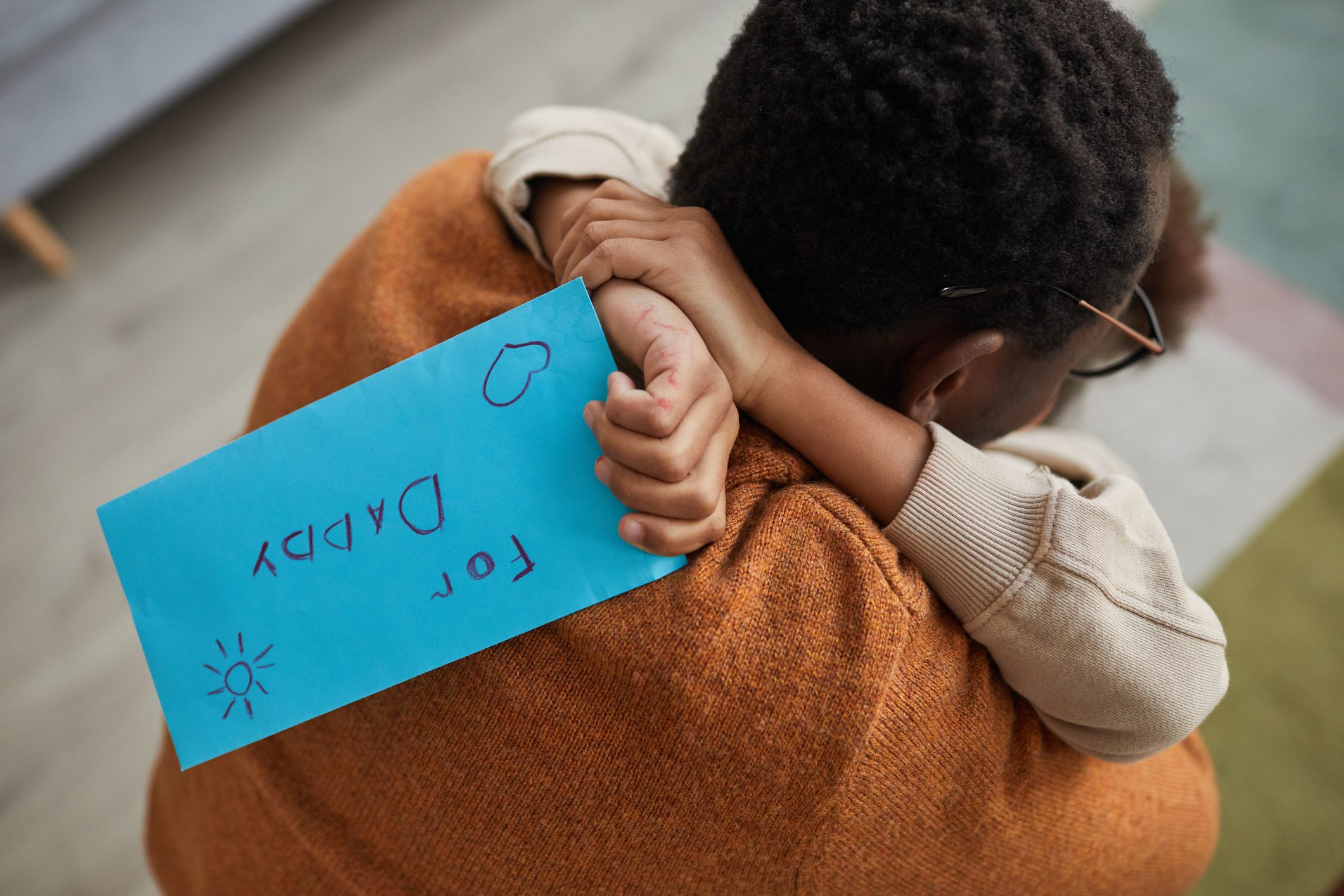 Close up of happy father embracing little girl after coming home from work on Fathers day, focus on child holding letter for dad,