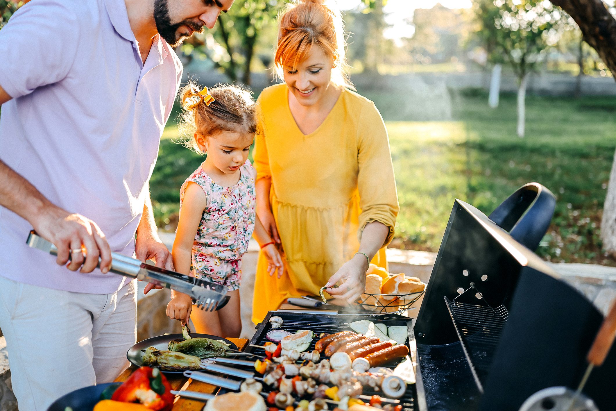 Family preparing meal in backyard on barbecue grill