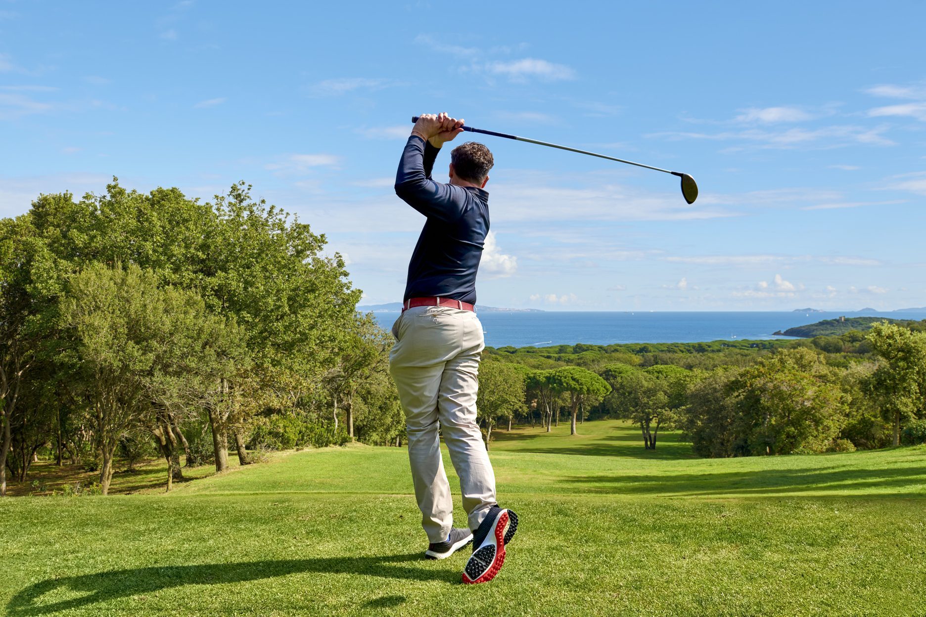 Golfer on the professional golf course. Golfer with golf club hitting the ball for the perfect shot.