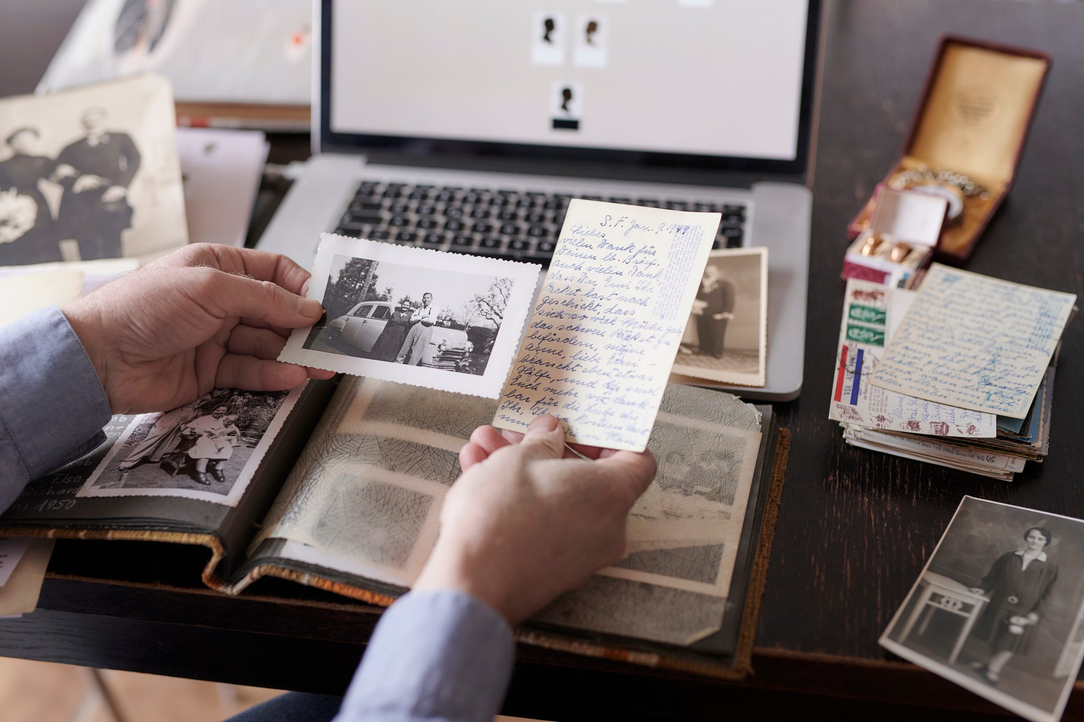 Man doing research on family members. Holding old photograph and postcard in his hands, close-up