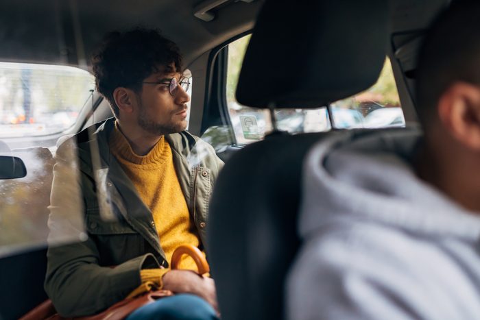 Portrait of a worried young man in back seat of car looking out of window