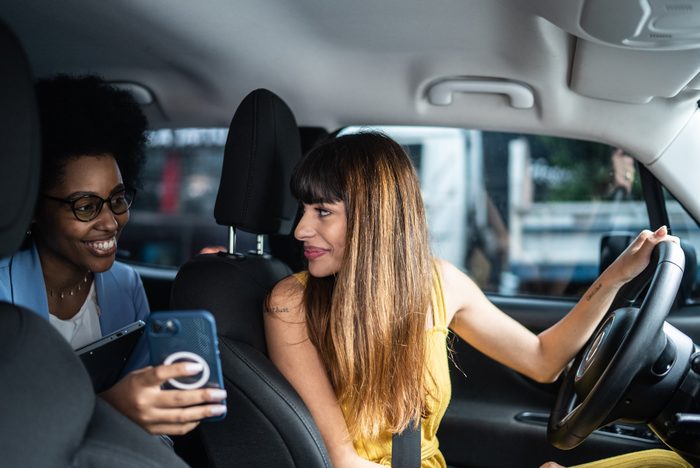 Passenger talking to cab driver and showing her the smartphone