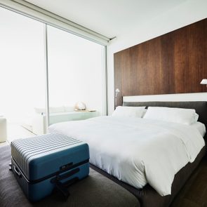 Wide shot of suitcase at end of bed in luxury hotel room