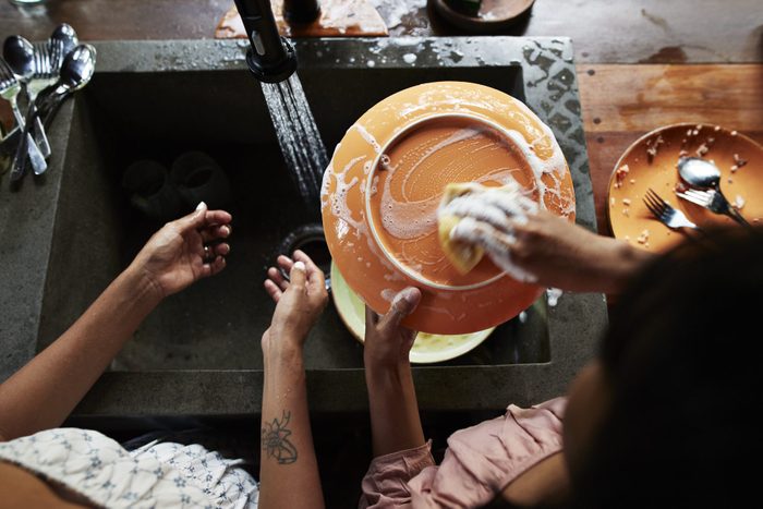 Mother and daughter washing plate in kitchen