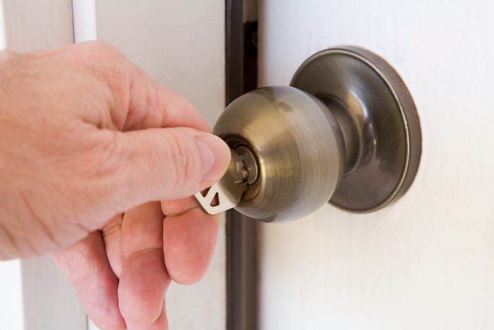 hand unlocking and opening door with key