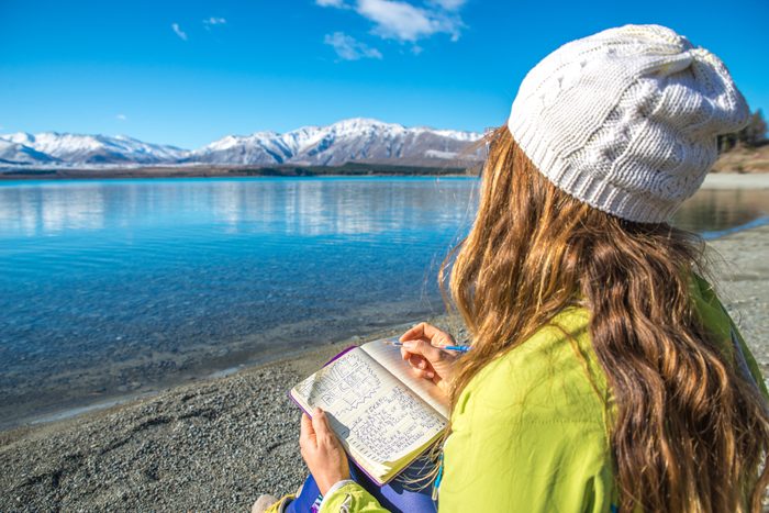 Happy Young woman writing a diary in nature