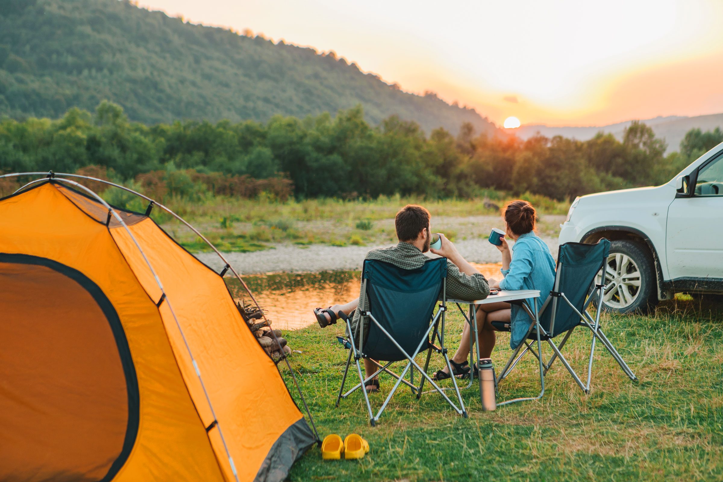 couple sitting in camp chairs next to an orange tent