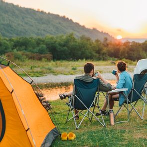 couple sitting in camp chairs next to an orange tent