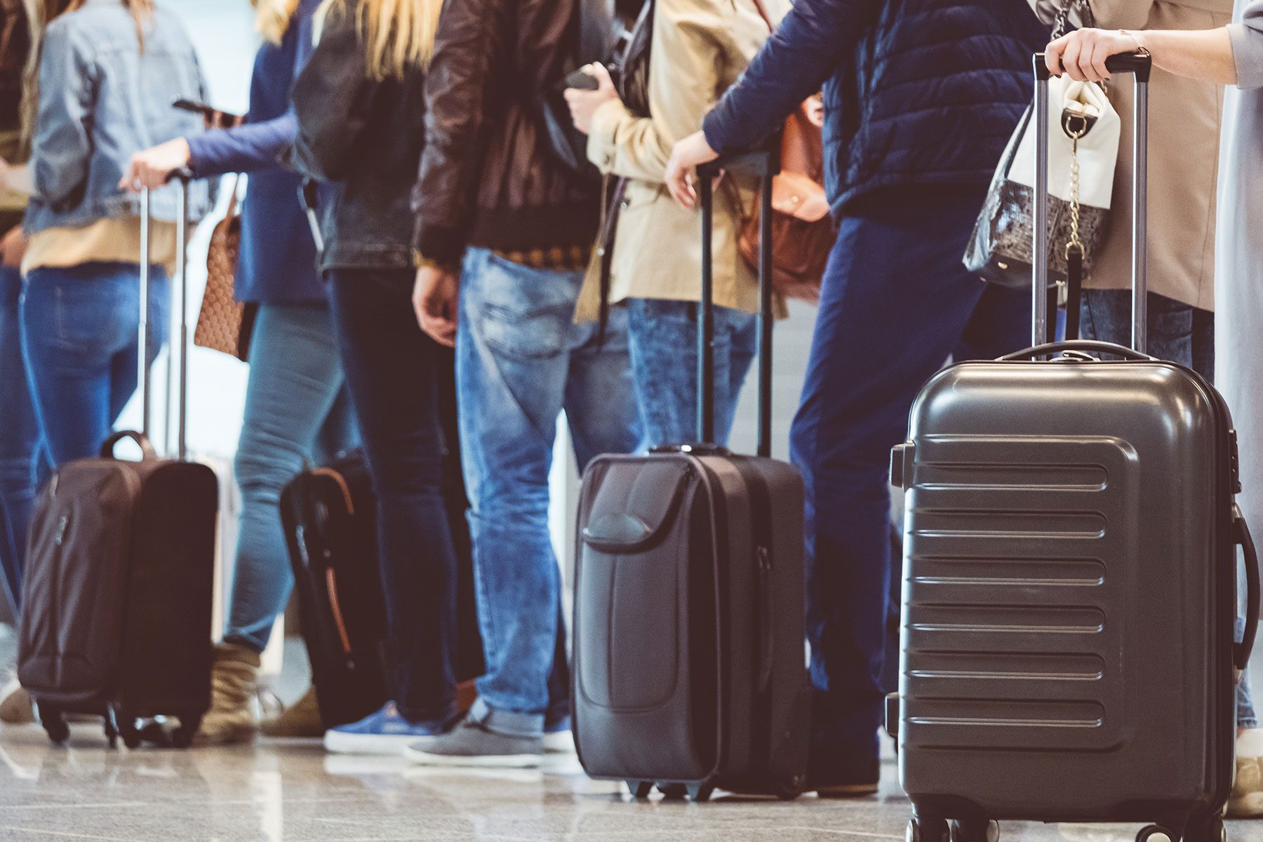 Shot of queue of passengers waiting at boarding gate at airport