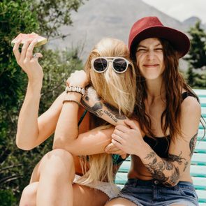 Happy oddball girlfriends embrace outdoors with watermelon in hand