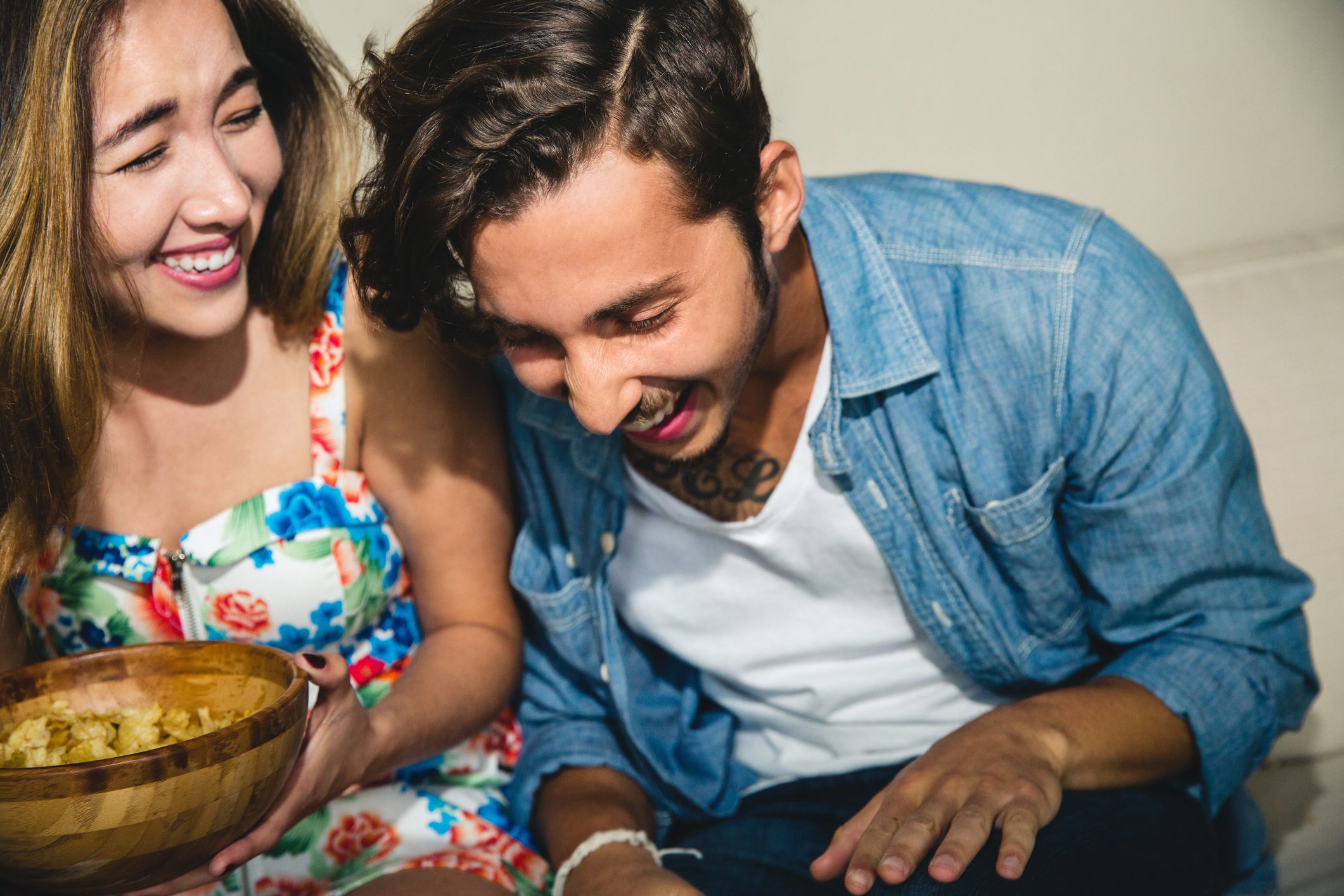 Cheerful young friends laughing while sitting on sofa during party