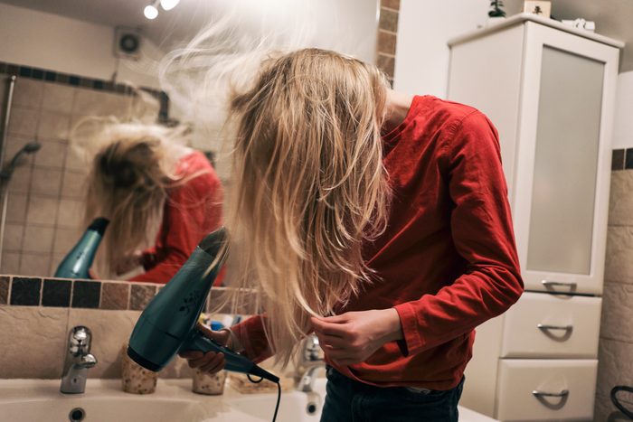 Teenaged boy having fun with blow dryer