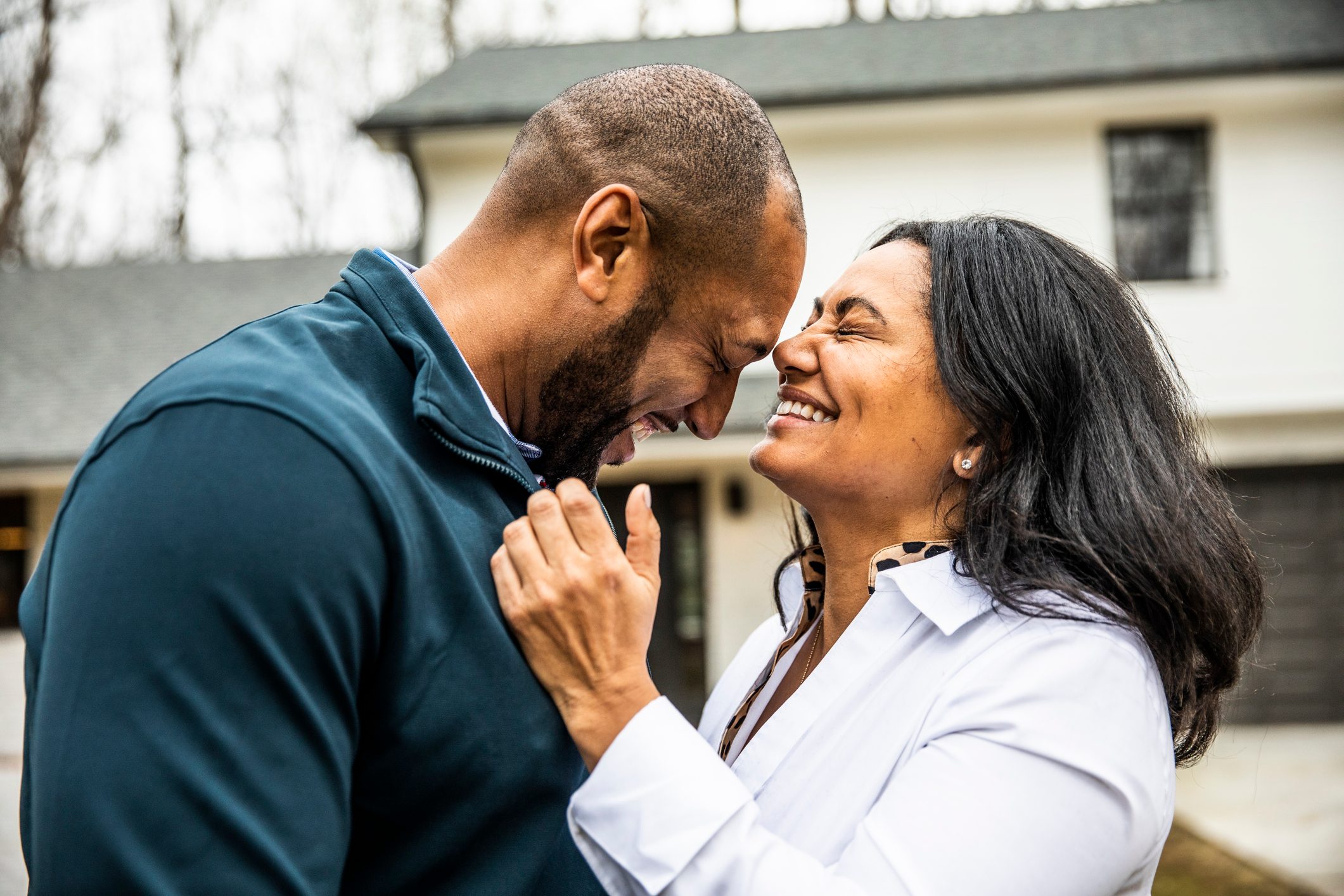 Married couple embracing in front of residential home