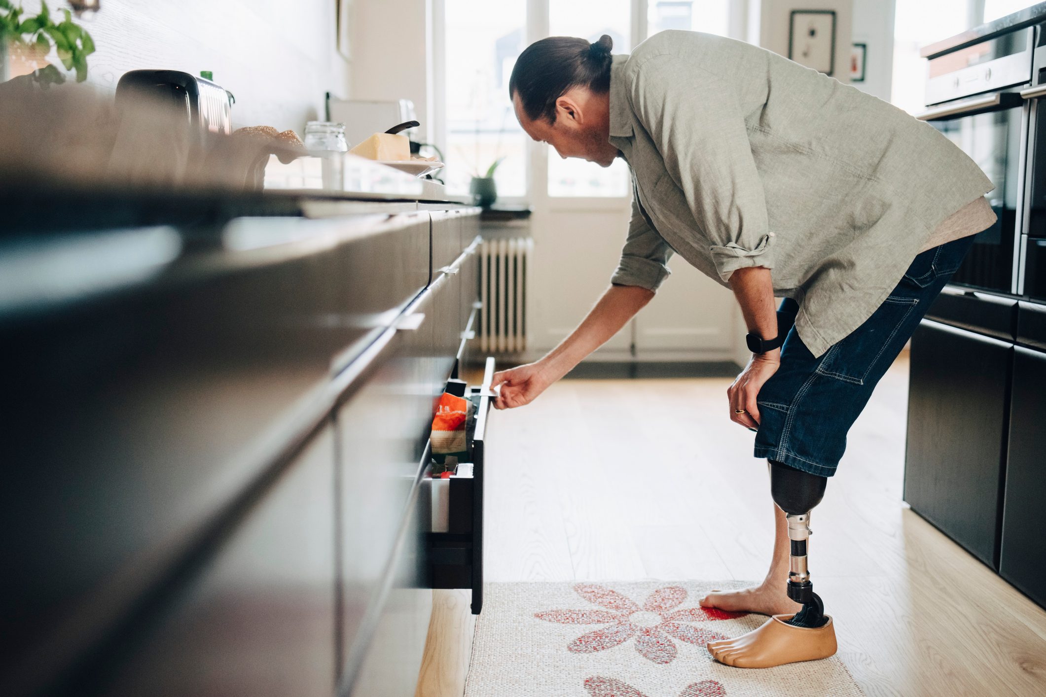 Disabled man opening drawer in kitchen at home