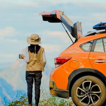 woman traveler in motion of enjoying takes a look scenery view on the peak of mountain at the morning light, joyful taking mind cheerfully with set of hot coffee time on the cliff of mountain, hight range of the risk area camping