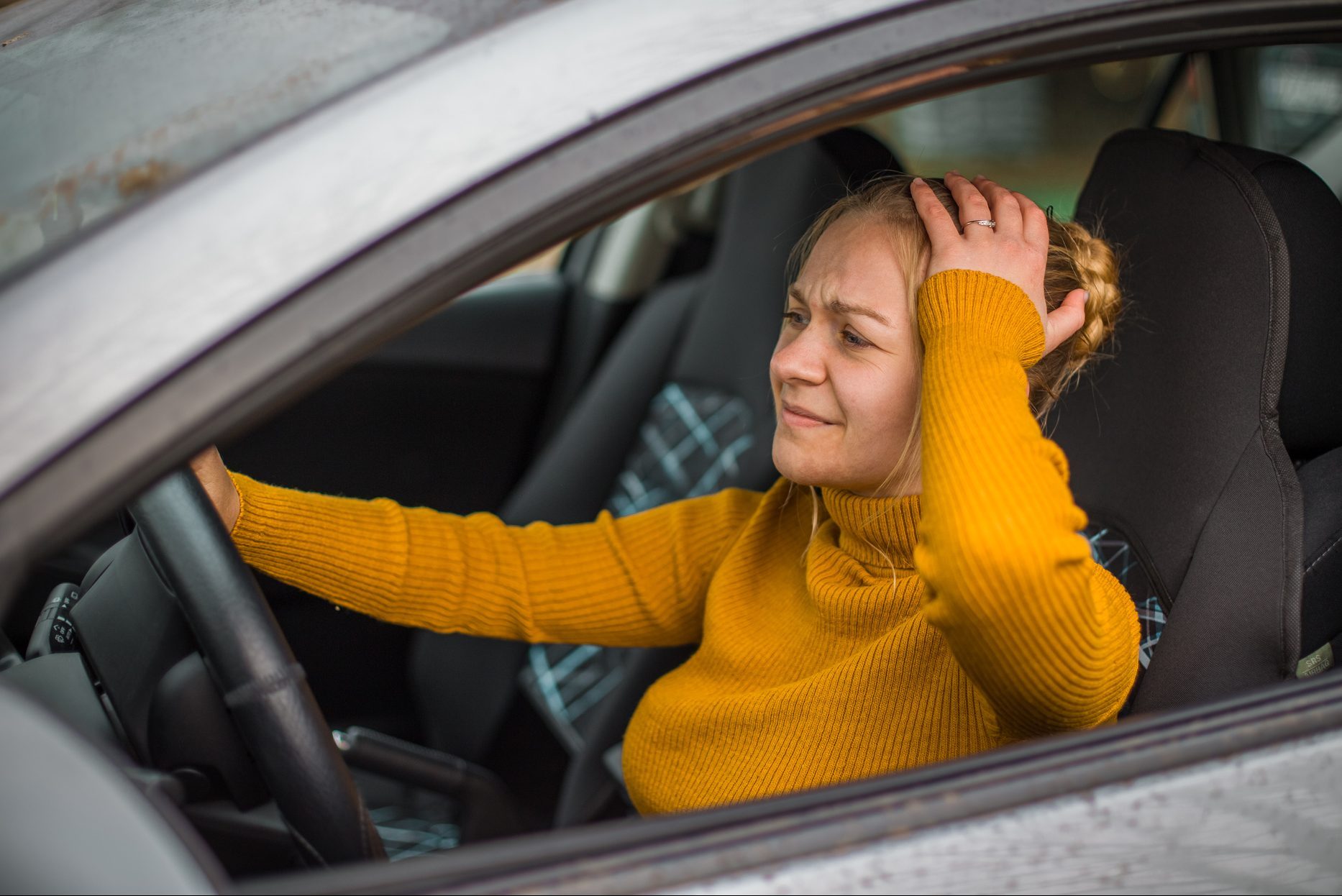 Young woman sitting in her car and having problem