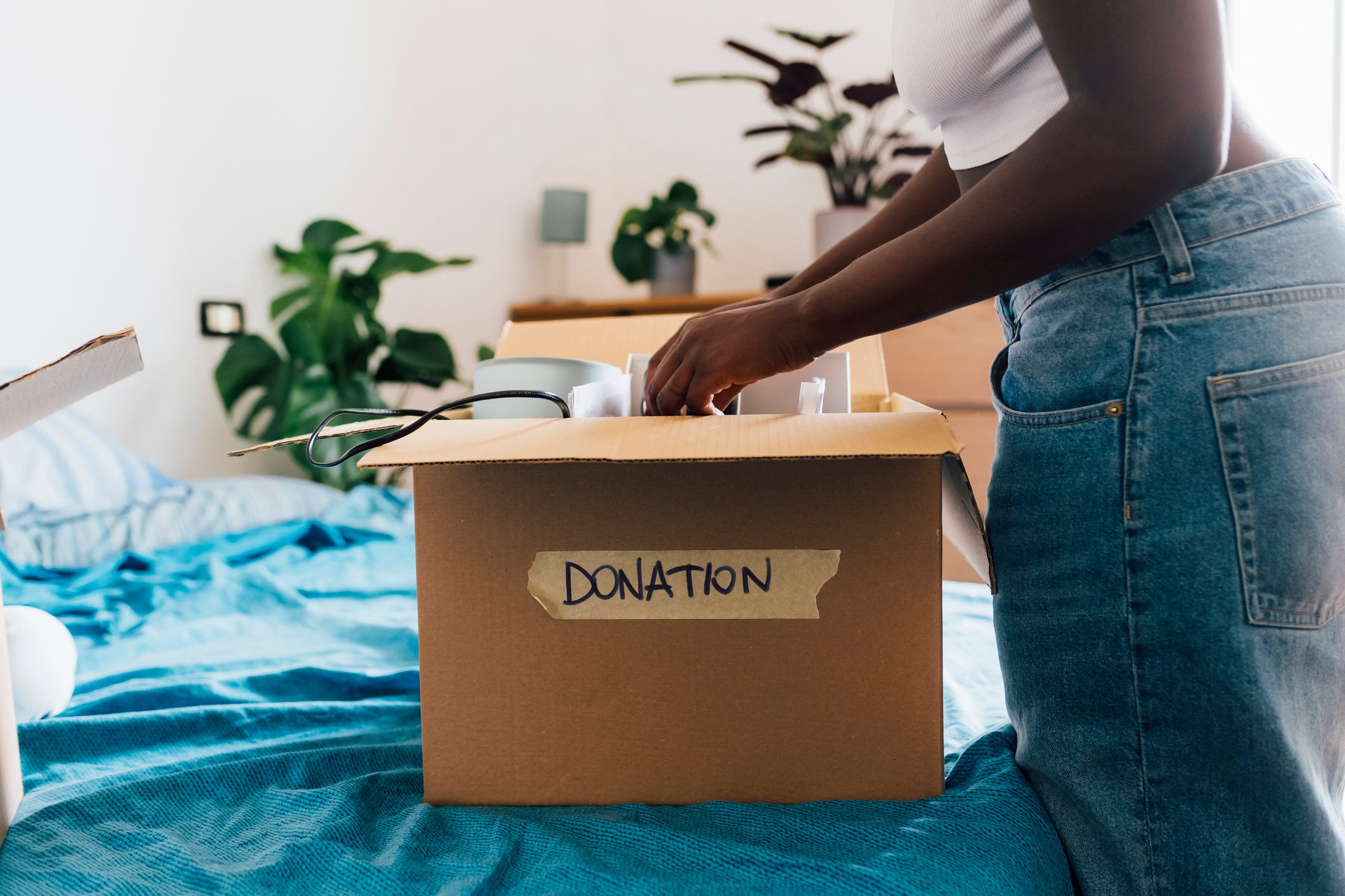 Woman packing donation box on bed at home