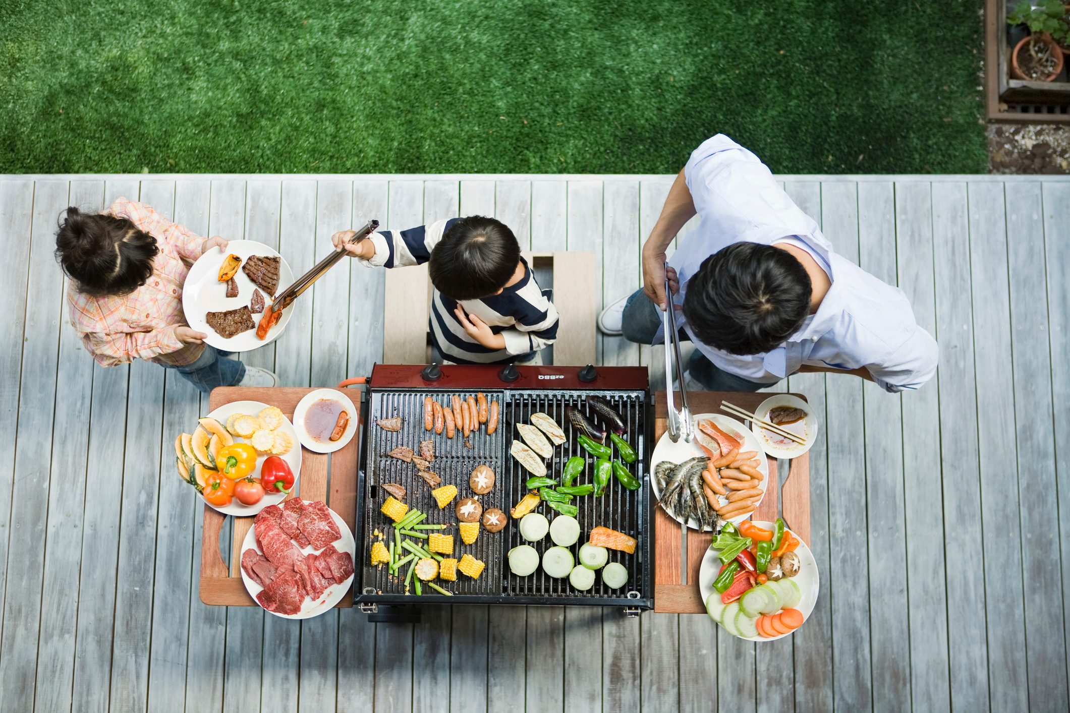 Man and boy cooking barbecue for family