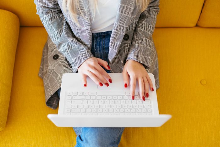 Businesswoman sitting on yellow couch, using laptop