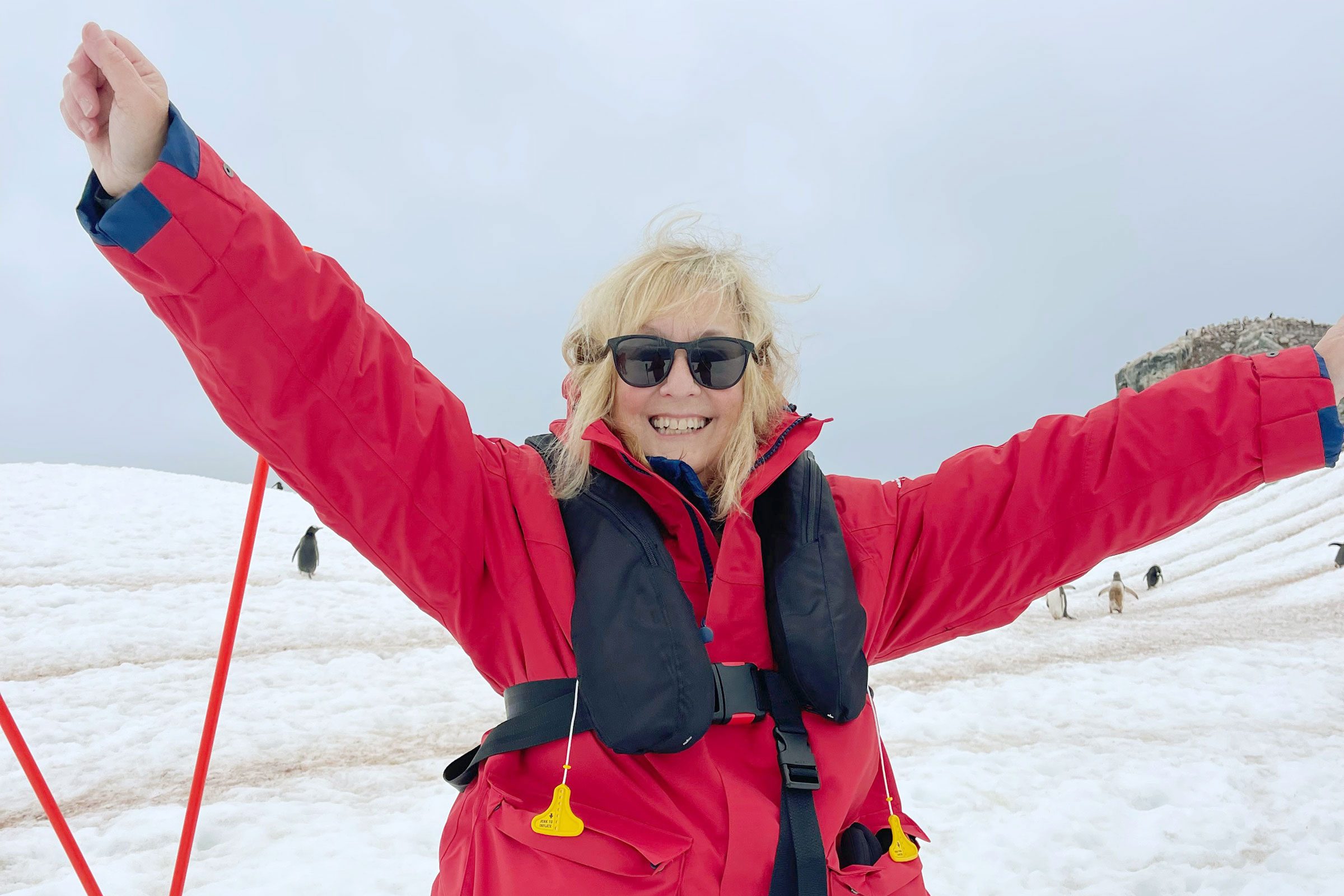 portrait of woman in a red winter coat with her hands up in the air
