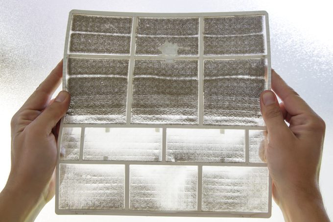 Man Holding Very Dirty Air Conditioner Filter against the light to spot dust and debris in the filter
