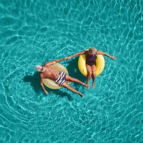 High angle view photo of a senior couple floating in the ocean while using swimming and floating devices