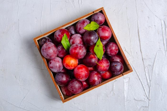 Fresh plums fruit on white gray stone background