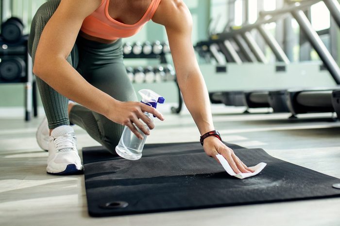 Happy athletic woman disinfecting exercise man before working out in a gym.
