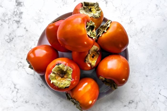 Persimmons on a plate on white background