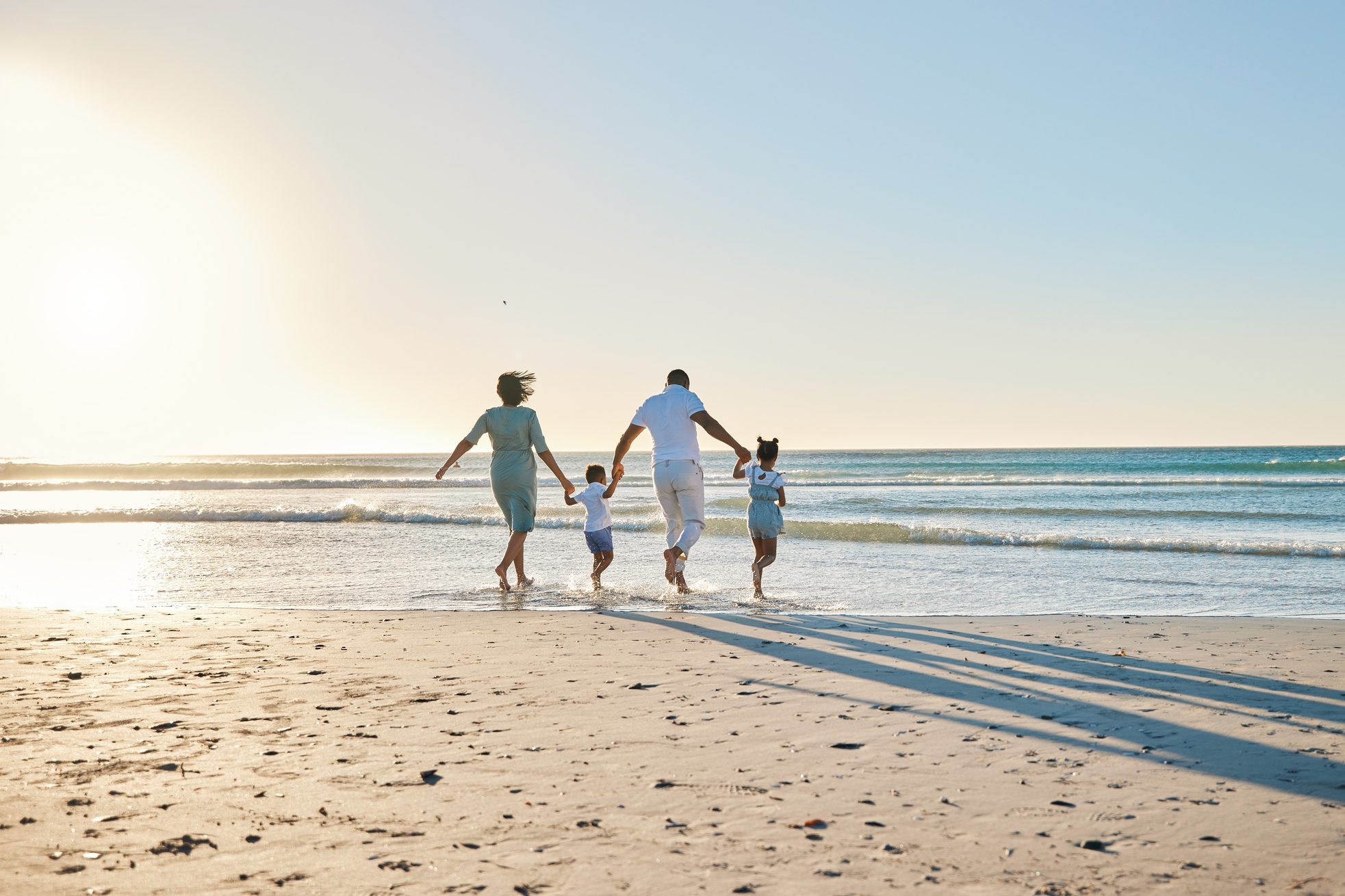 Rearview shot of a happy family walking towards the sea