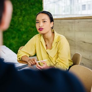 Office Manager Talking To Colleague At Her Desk