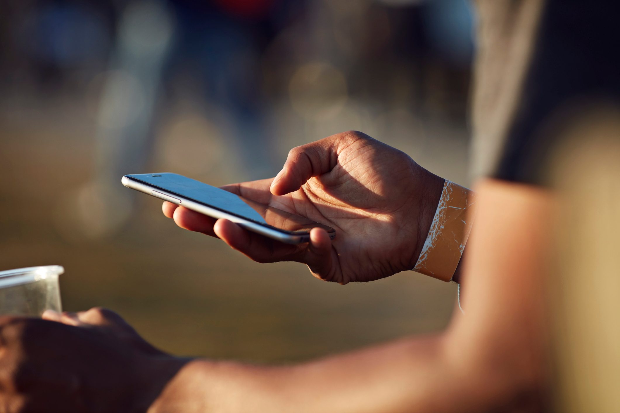 Close-up of hand scrolling on phone at festival