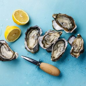 Open Oysters and lemon on blue background