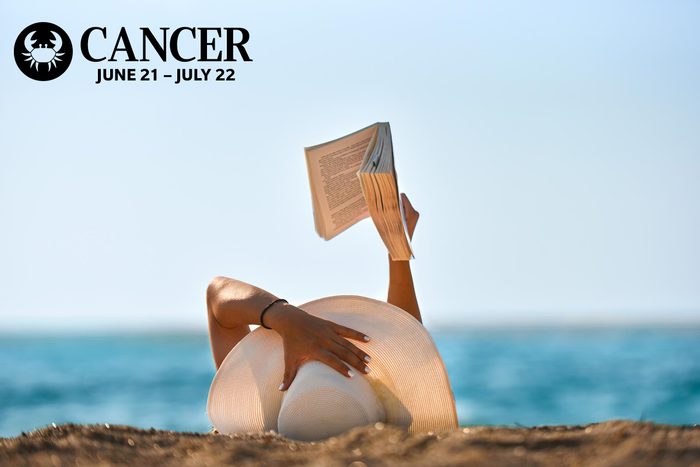 woman i na sun hat reading on the beach