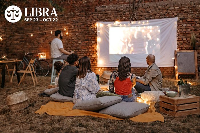 group of friends watching a movie outside on a projector screen