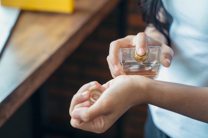 Young woman with bottle of perfume at home